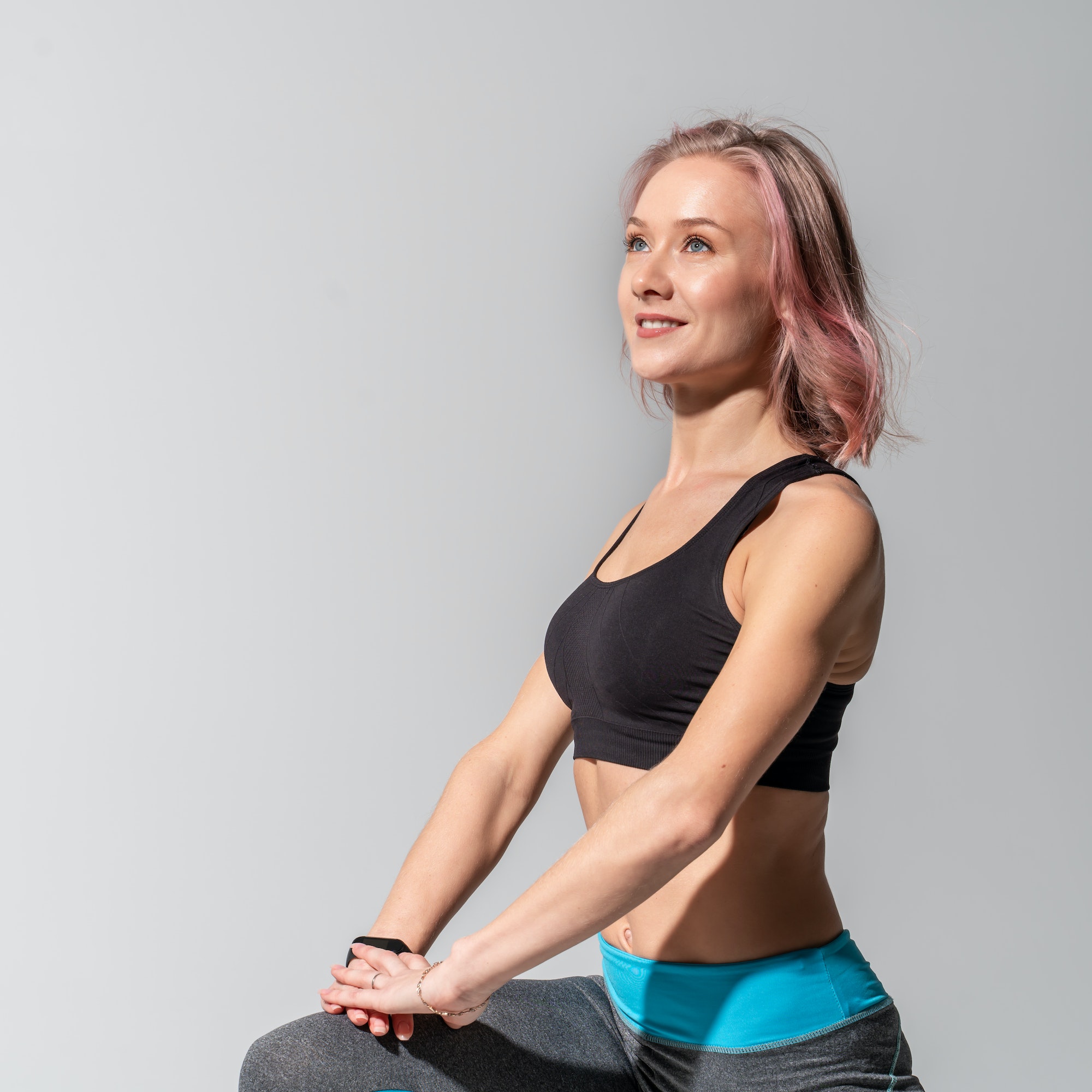 Caucasian girl doing sports exercises for stretching muscles on a gray studio background